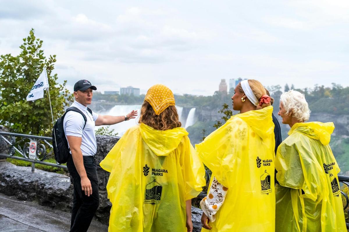 a group of people in raincoats looking at a waterfall