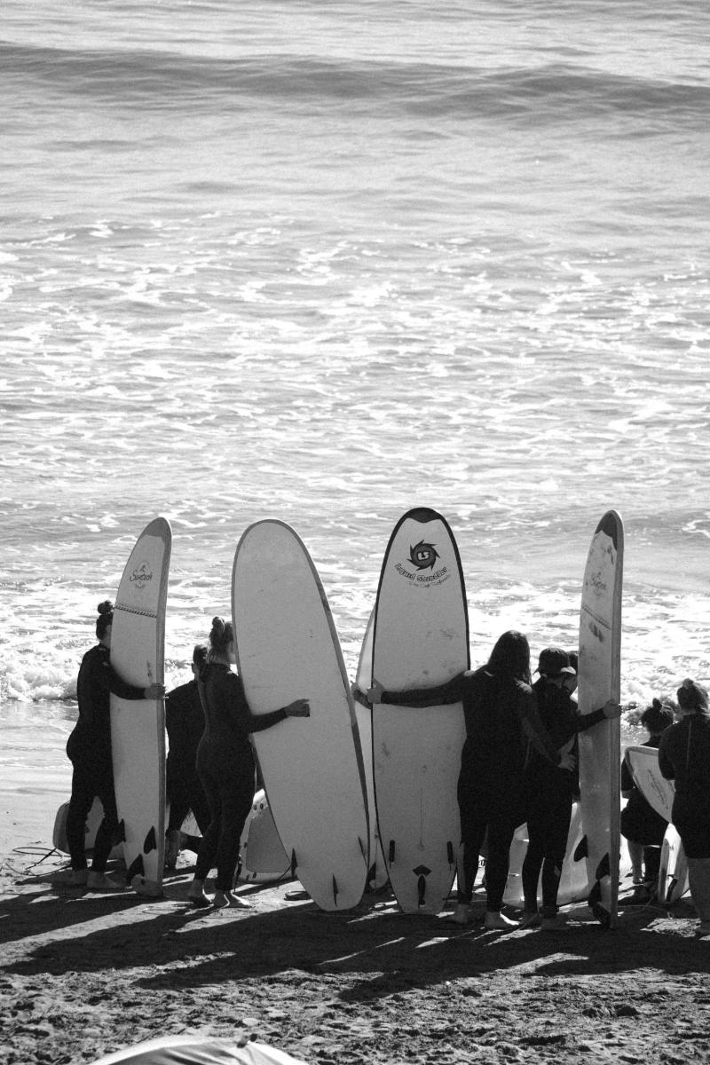 a group of people standing on the beach with their surfboards