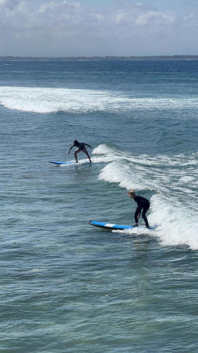 two people riding waves on surfboards in the ocean