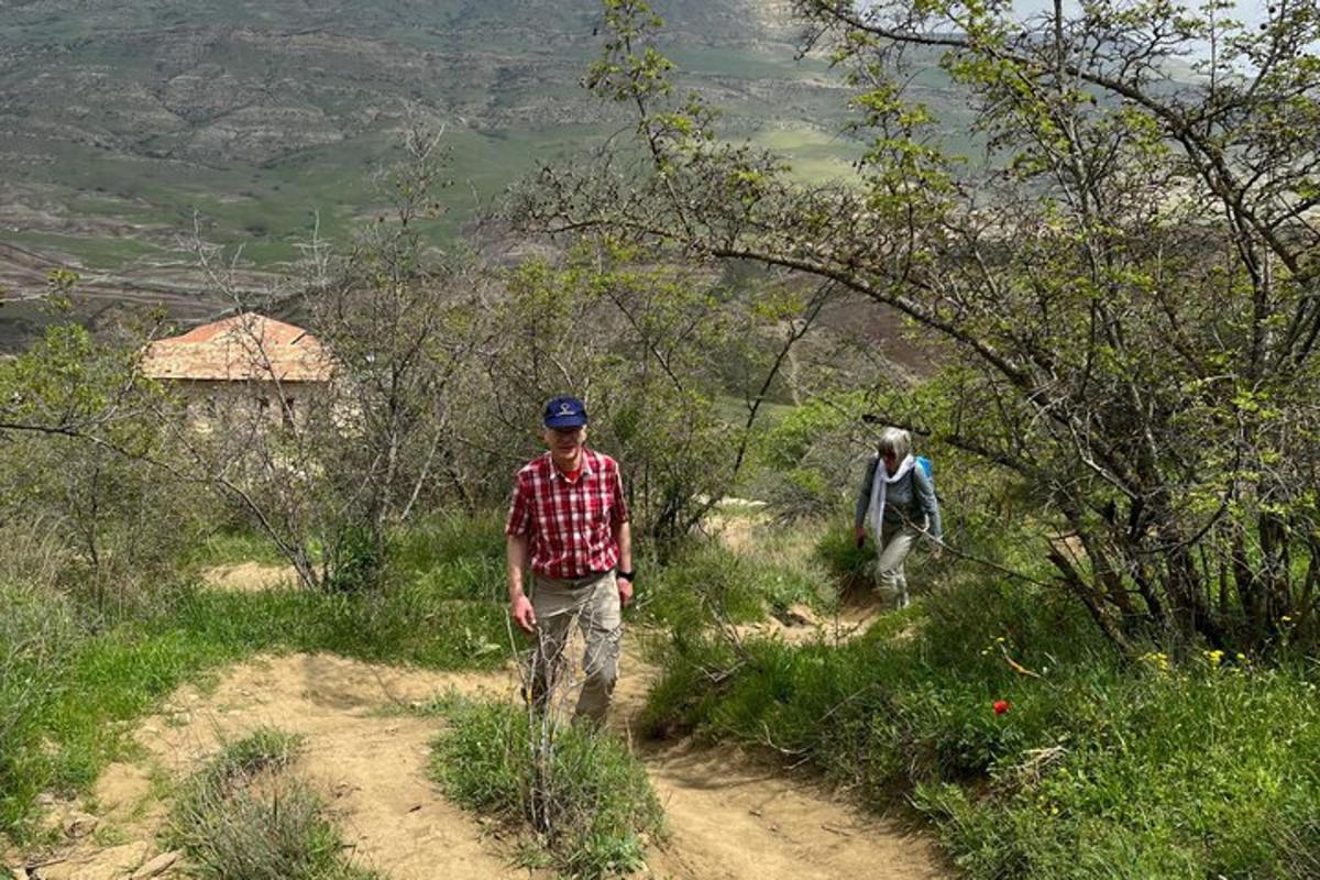 two men walking on a dirt path on a hill