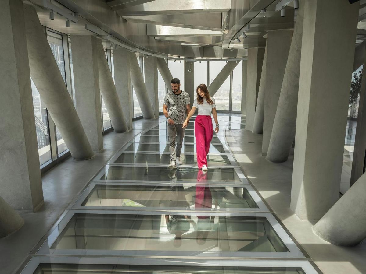 a man and a woman walking down a glass floor in a building