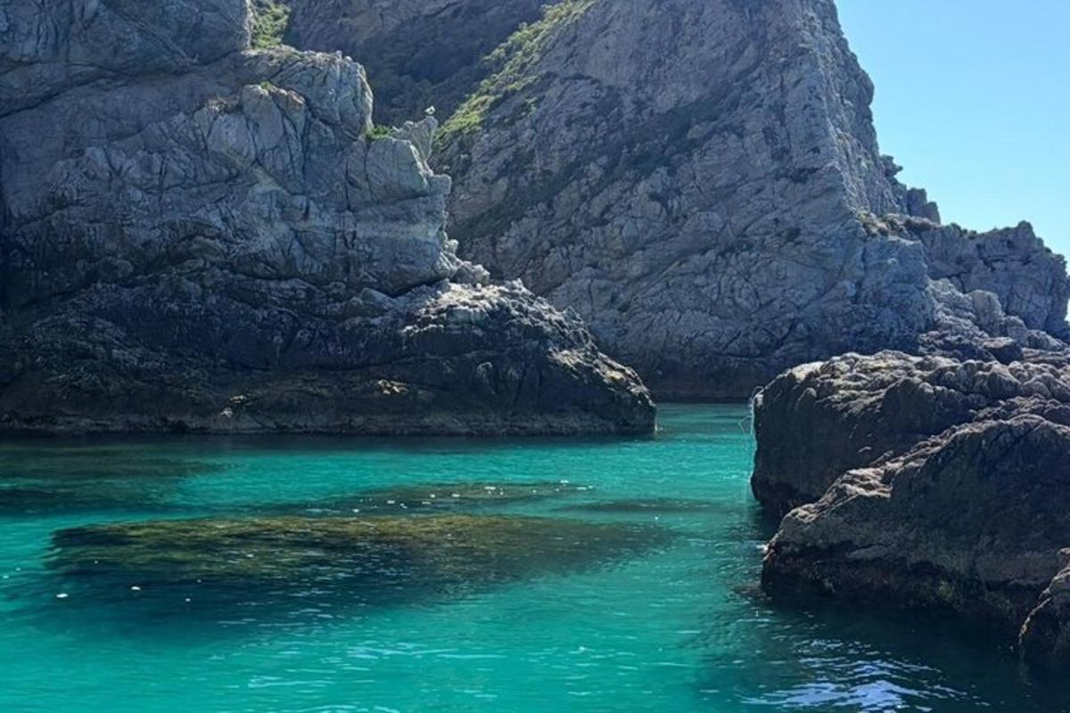 un cuerpo de agua al lado de una montaña rocosa