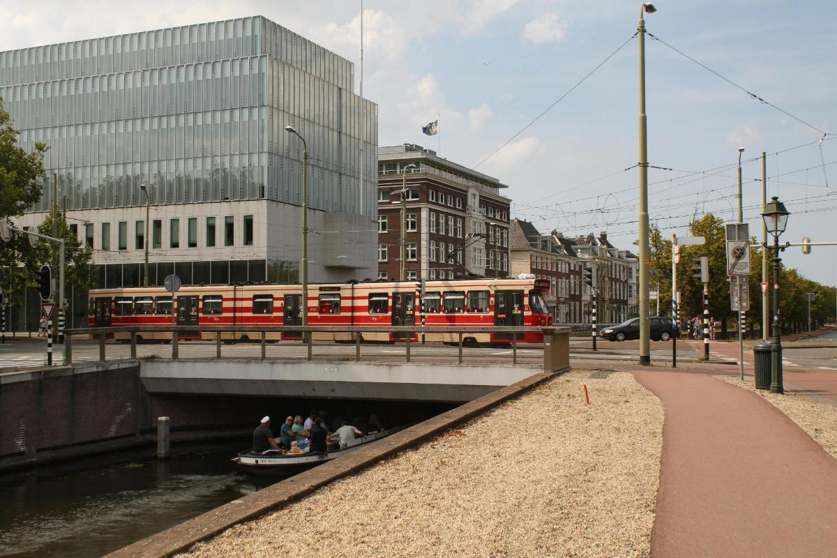 a train on a bridge over a river with people in a boat