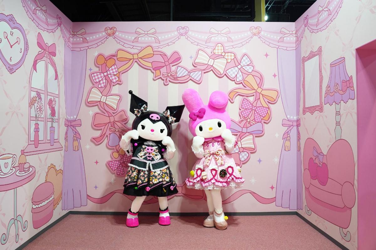 two dolls are standing in a pink room