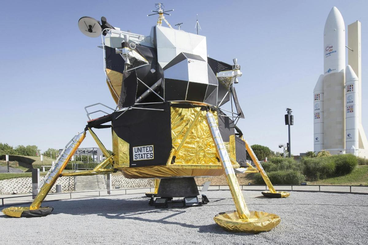 a spacecraft sitting on display in a parking lot