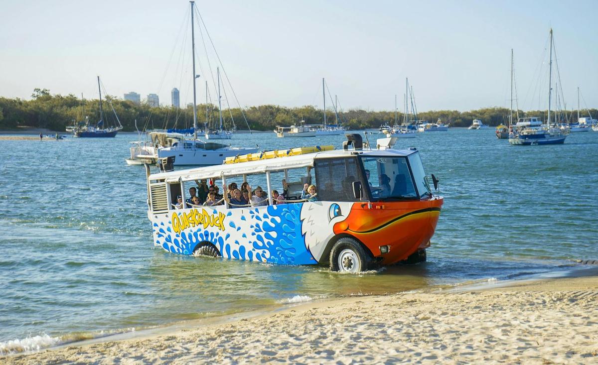 a bus driving in the water on a beach