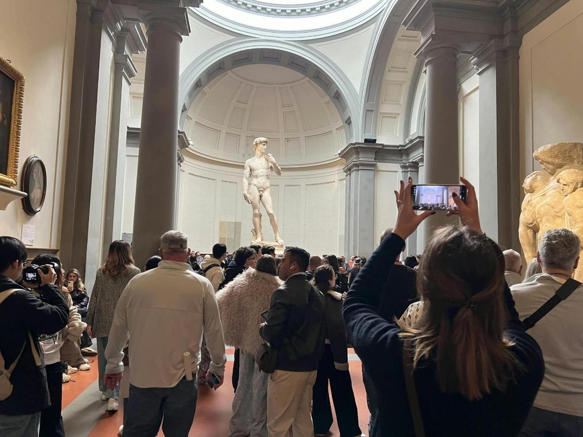 a crowd of people taking pictures of a statue in a museum