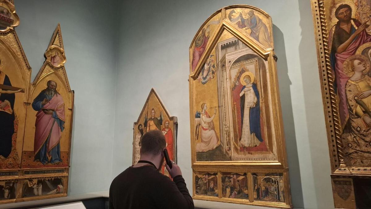 a man taking a picture of paintings in a museum