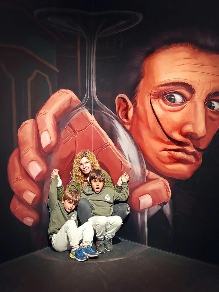 two children sitting in front of a painting of a hand