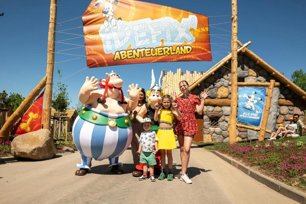 a family posing in front of a disneyland sign