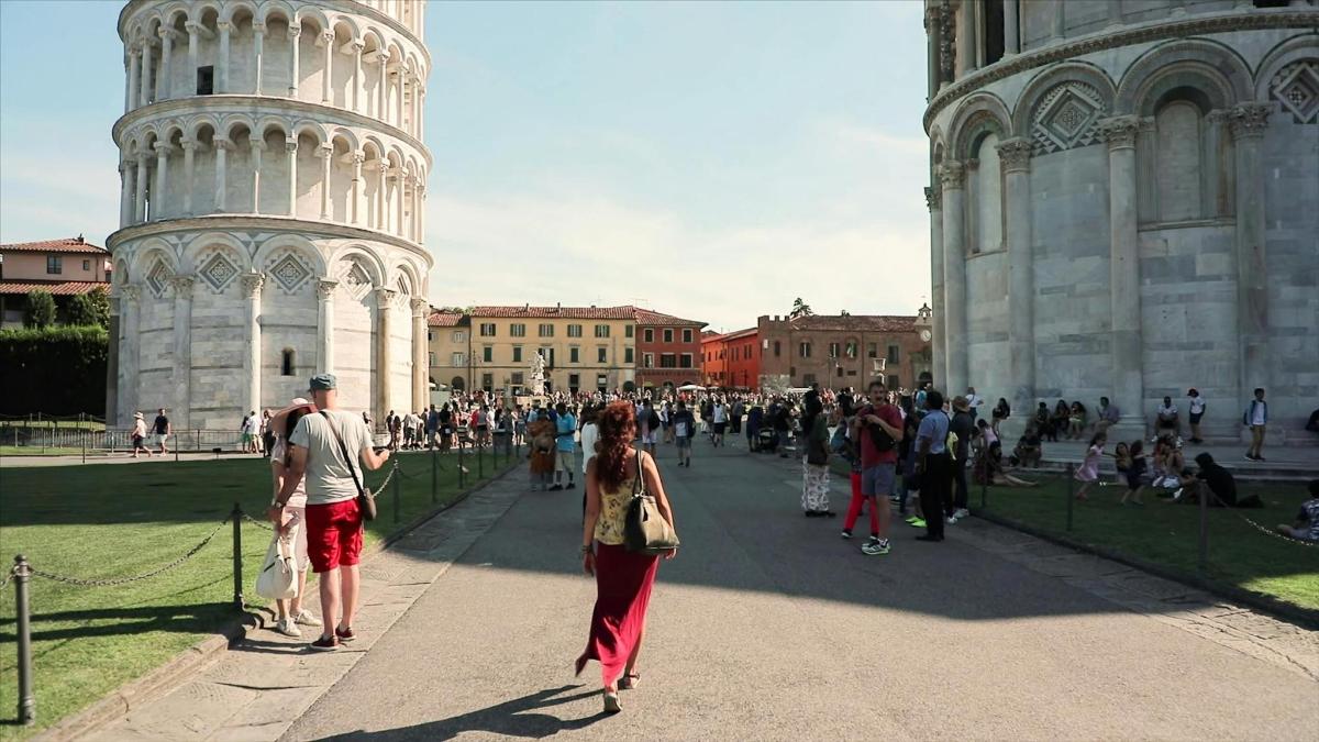 a group of people walking in front of the leaning tower
