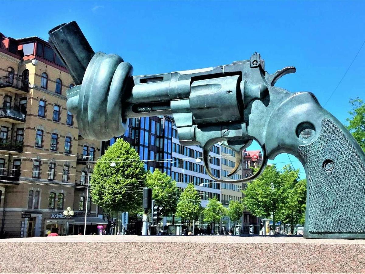 a metal gun statue in front of a building
