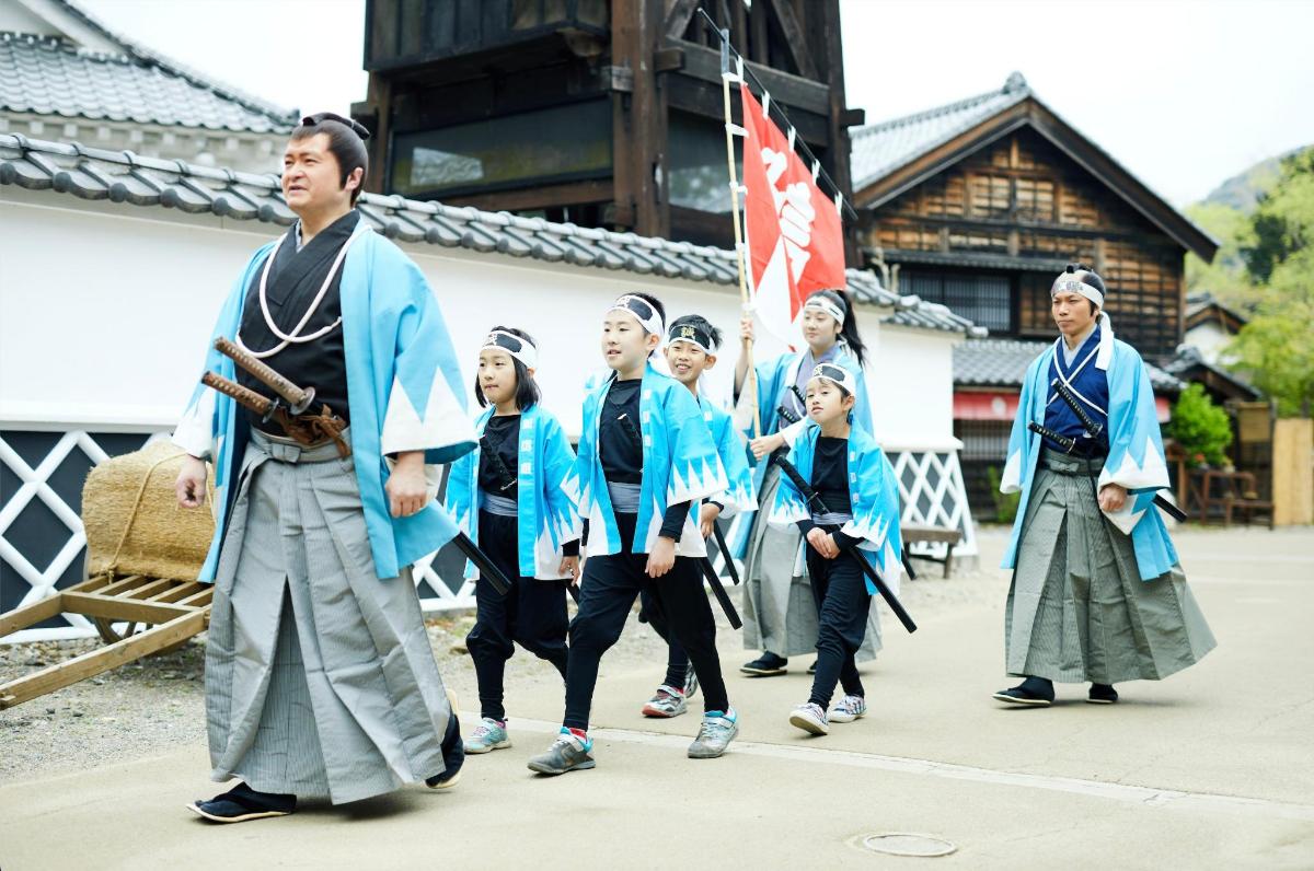 a group of children in kimonos walking down a street