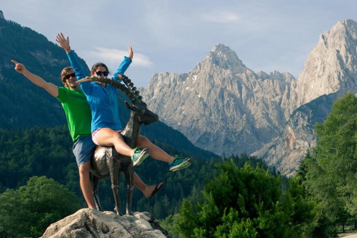 two people jumping on top of a statue on a mountain
