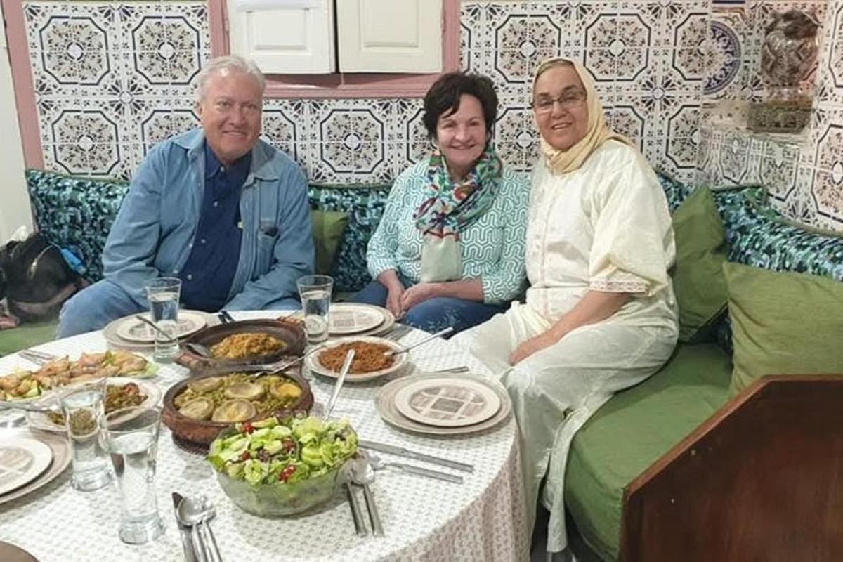 a group of three people sitting at a table with food