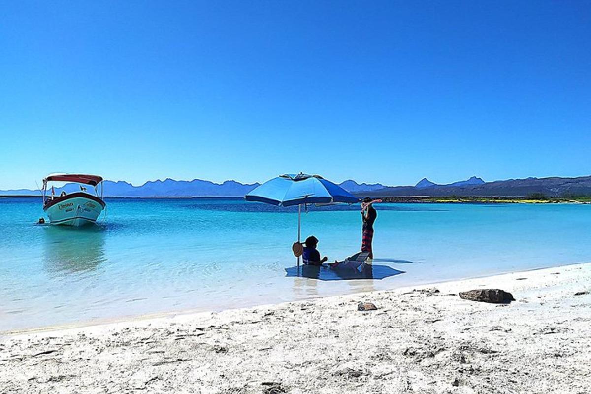 a group of people sitting under an umbrella on a beach