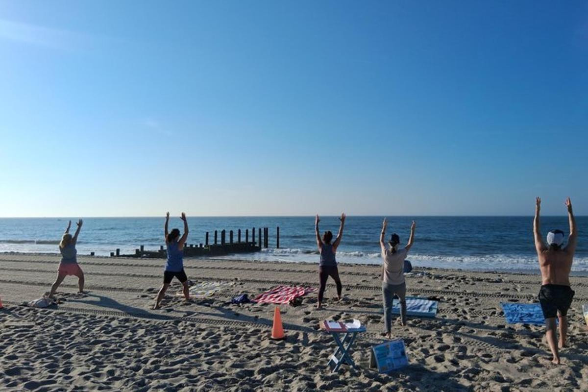 a group of people doing yoga on the beach